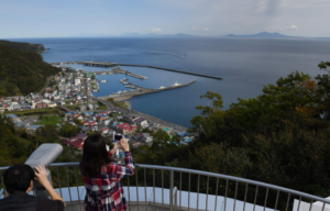 Man and woman looking out over the open water with binoculars