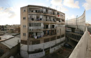 A curved building in disrepair, a road on the right