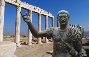 Background: Columns located at the side of the Western Agora. Foreground: Bronze statue of Trajan located at the London Borough of Tower Hamlets, 2011.