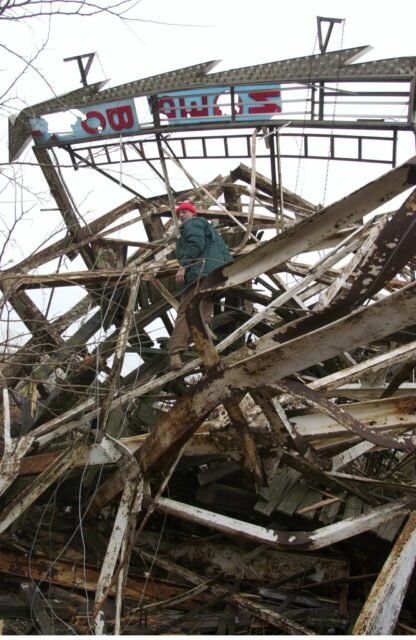Man climbing destroyed wooden roller coaster.