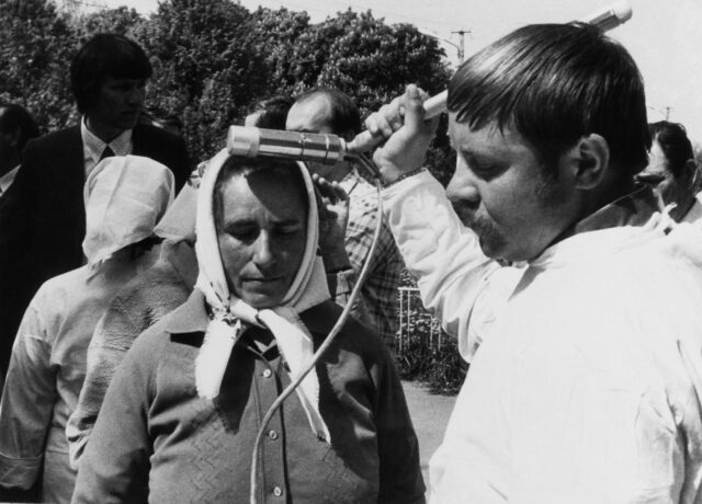 Man checks radiation levels from woman's forehead.