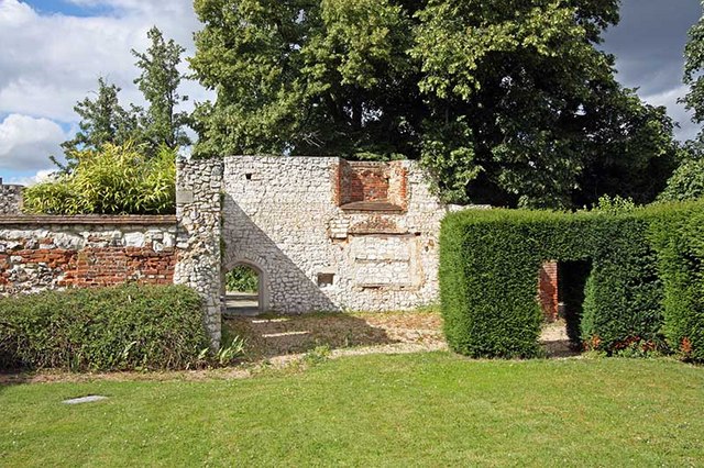 Stone wall peaking through greenery in a garden