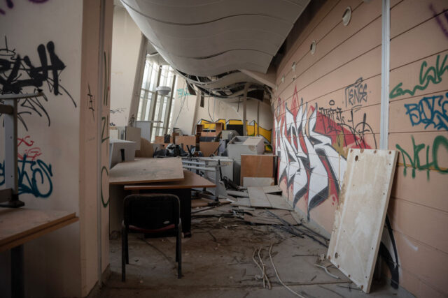 Hallway filled with debris, with graffiti on the walls