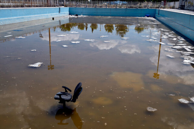 Algae-filled swimming pool, with garbage floating in the water