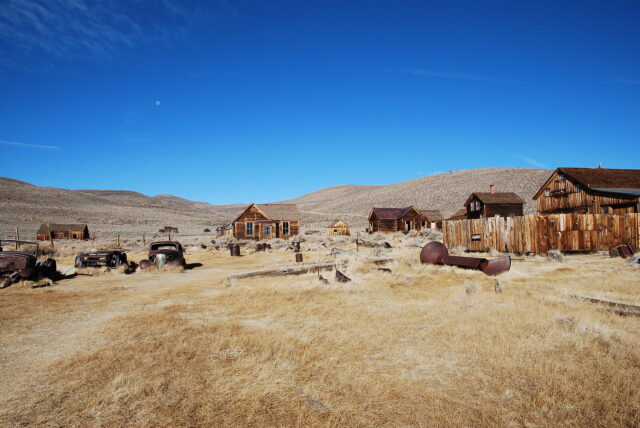 Wooden structures and abandoned cars in the middle of an open area