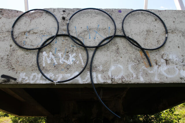 Destroyed Olympic Games logo attached to a cement wall