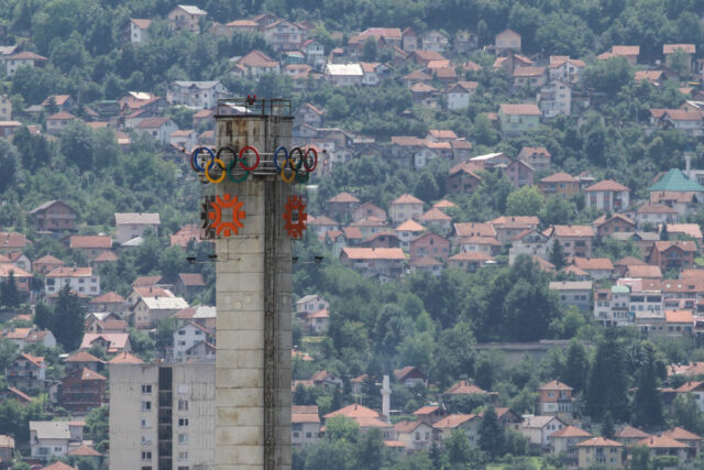 Tower rising above Sarajevo, Bosnia and Herzegovina, featuring the Olympic Games logo and another symbol