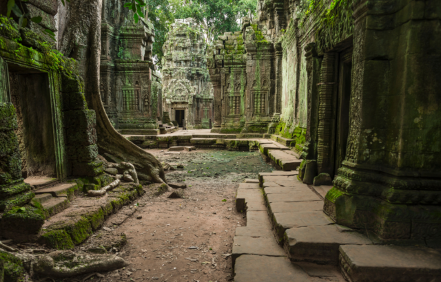 An ancient temple with tree roots growing over the structure.