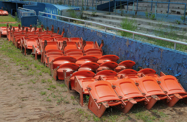 Rows of orange stadium chairs lined up against a wall