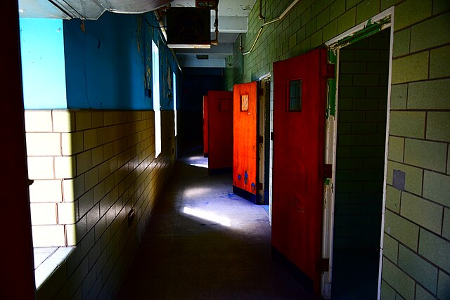 Doors partially open along a dimly-lit hallway