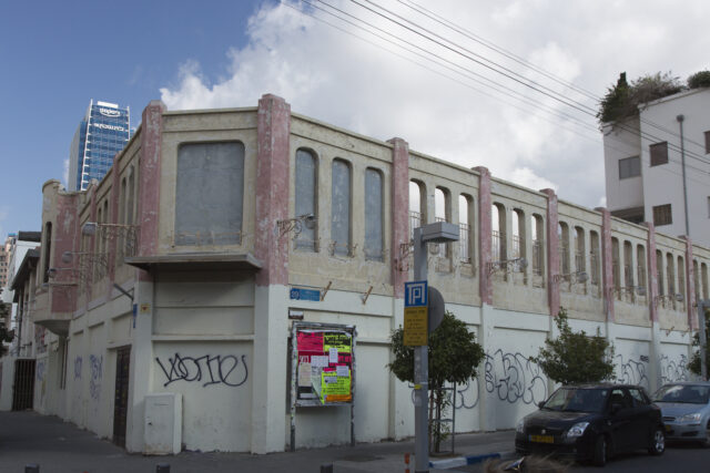 The exterior of a movie theater on the corner of a street.