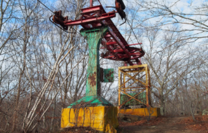 Rusting amusement park ride in the middle of a slightly-wooded area