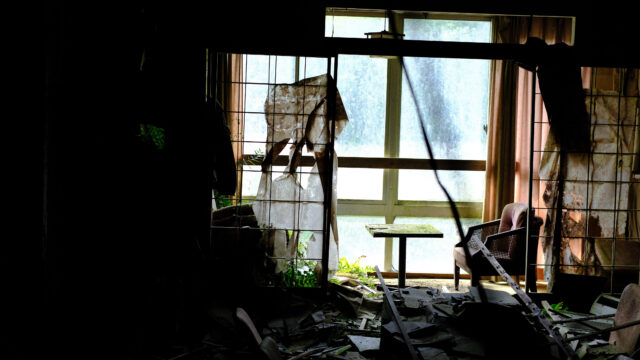 Debris and furniture strew across a dimly-lit room