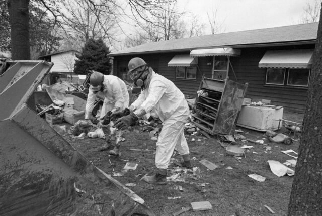 Personnel wearing hazmat suits, working outside of a house