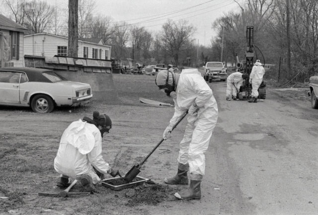 Workers in hazmat suits working along a residential street