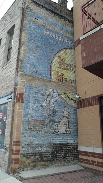 Partially-obscured ghost sign on the exterior of a brick building