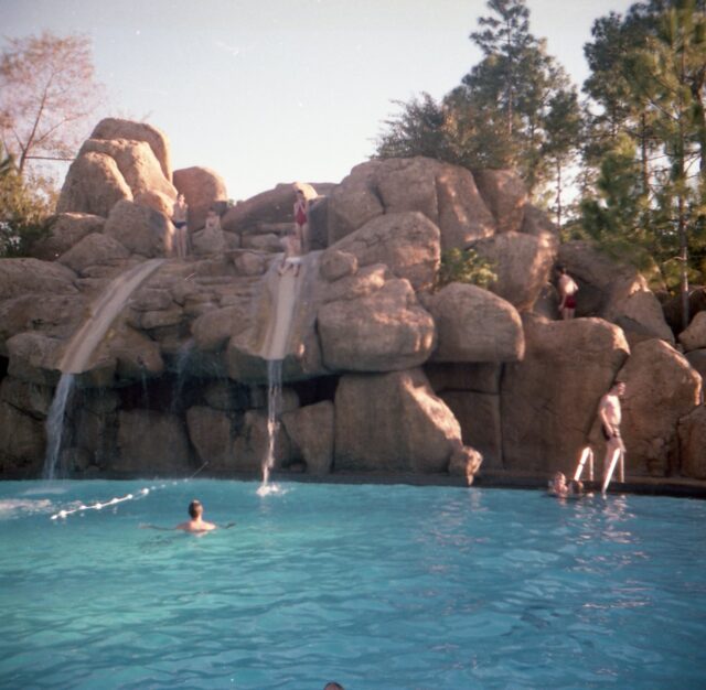 Guests swimming in a pool, while others wait to go down two rock-themed water slides