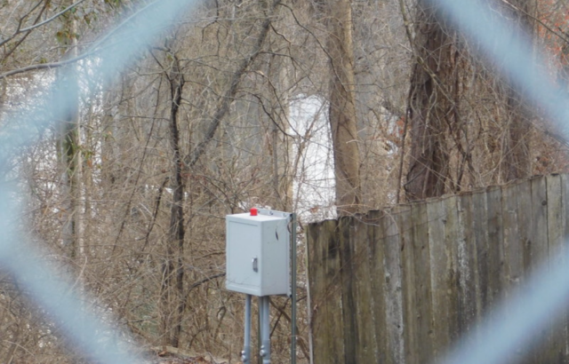 View of an outdoor power box through a chain link fence